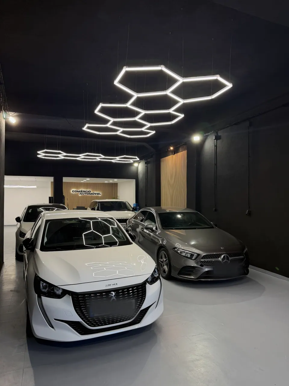 Espaço escuro com iluminação hexagonal e duas viaturas expostas
