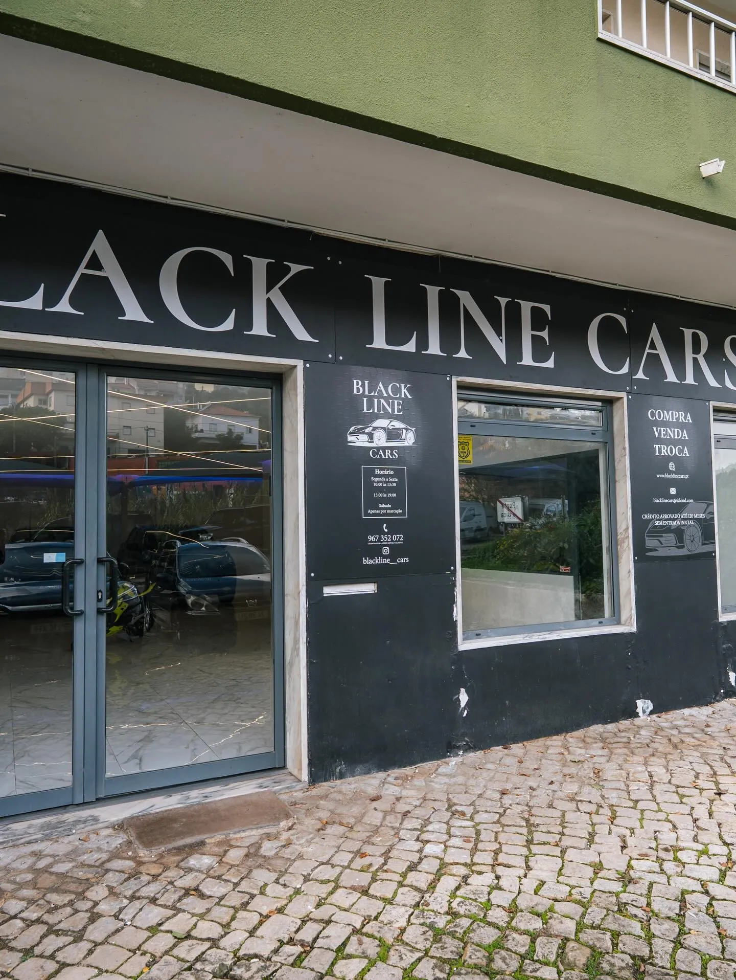 Fachada do stand com o nome Black Line Cars em maiúsculas serifadas sobre fundo preto